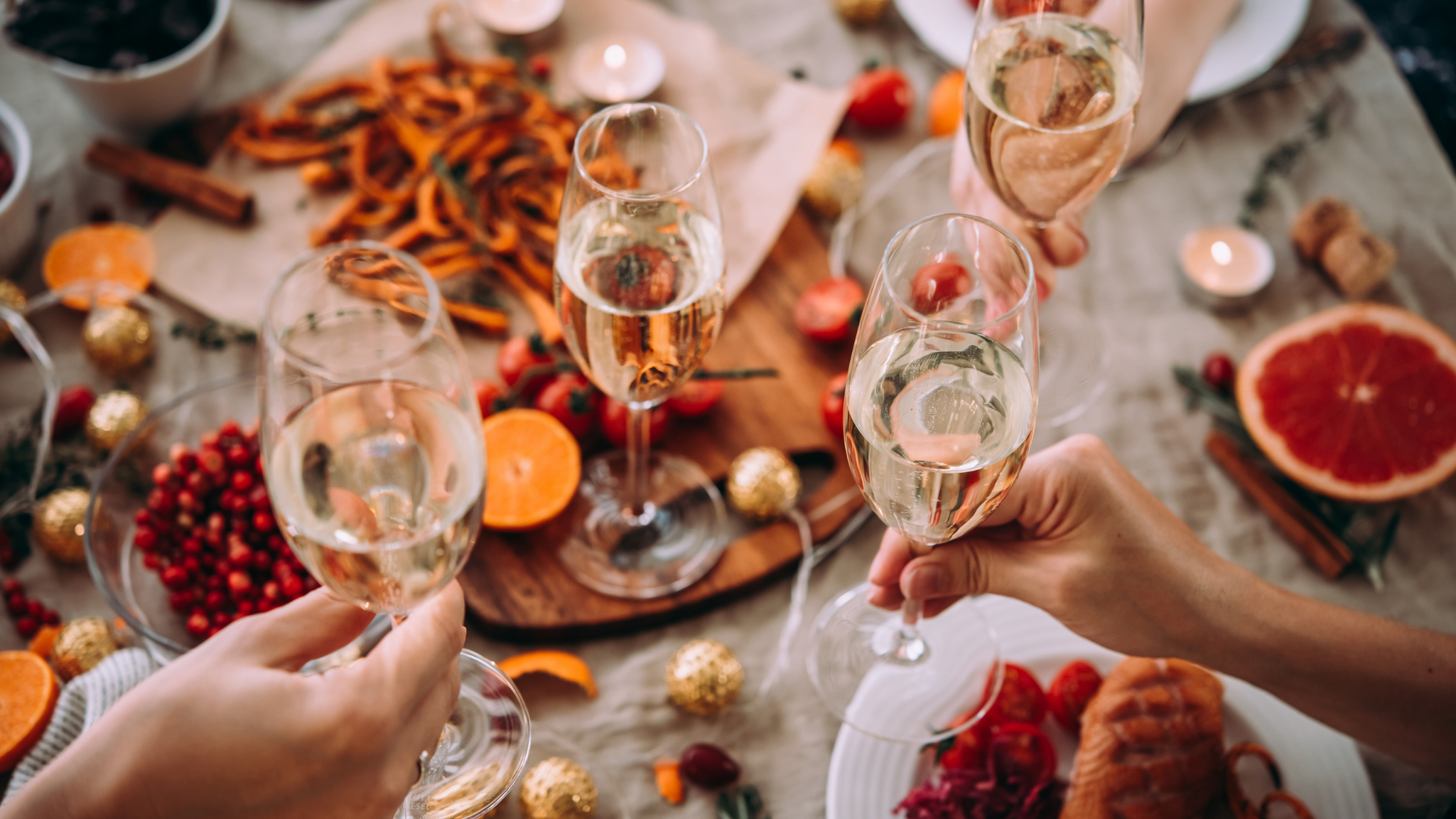 people cheers their champagne glasses over a table full of food and decorations