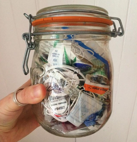 A medium sized jar with silicon-sealed lid is held up, full of various plastic garbage.
